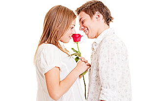 man in white dress shirt in front of woman in white top holding red rose